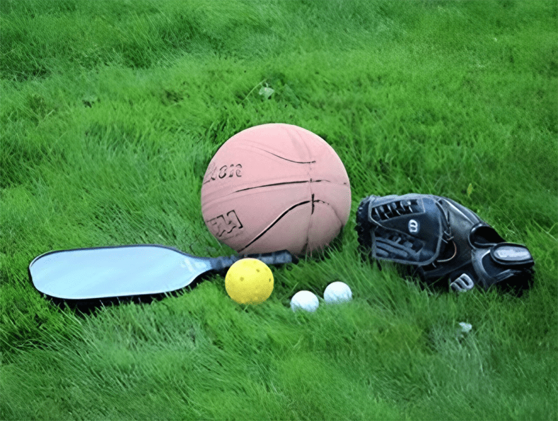 A basketball, tennis ball, and baseball placed on lush green grass, showcasing different sports equipment