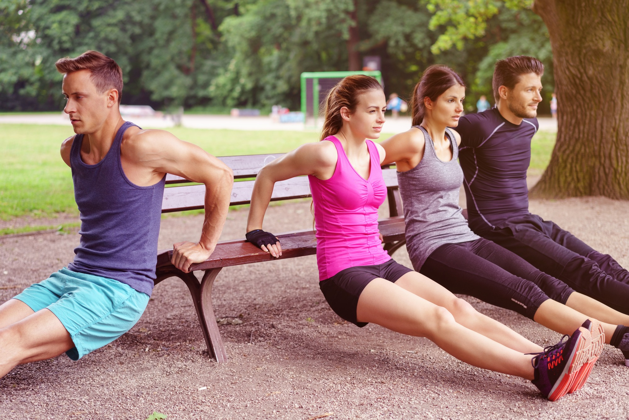 Group of adults performing dip exercises on park