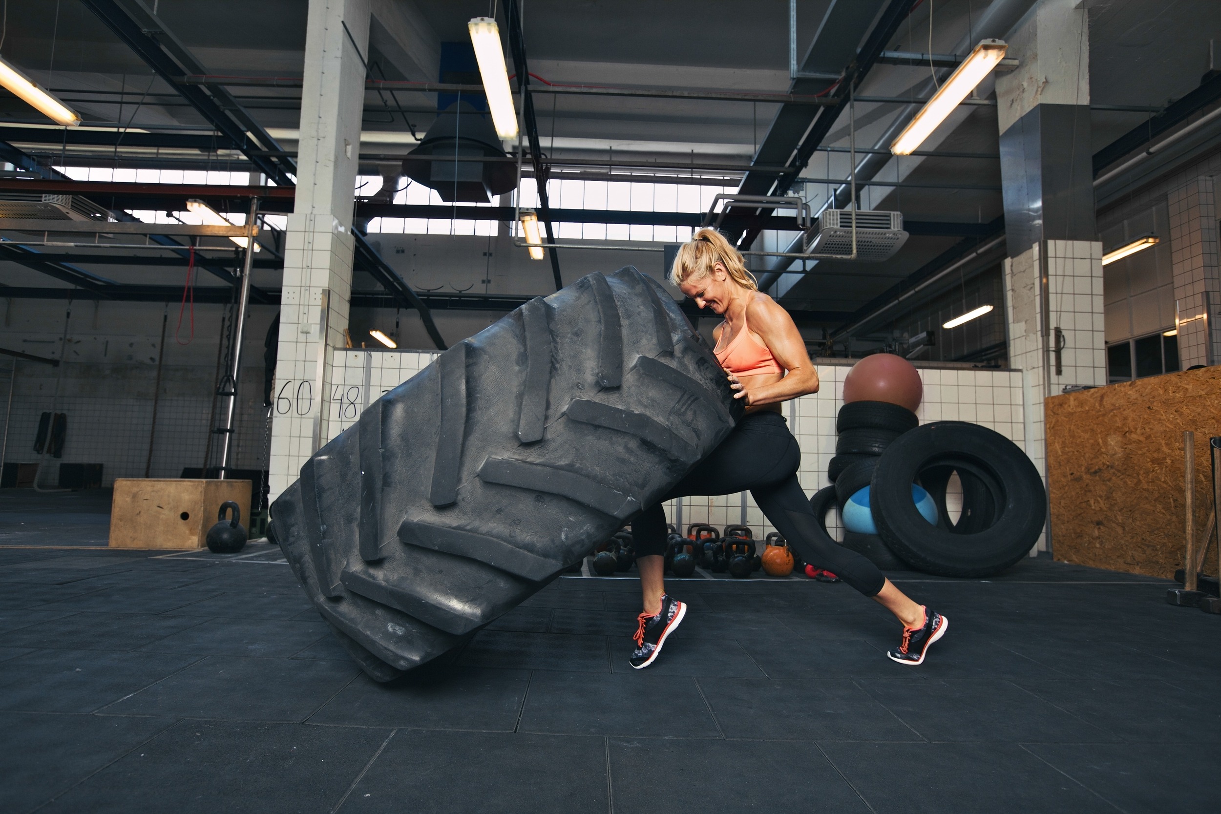 Fit female athlete working out with a huge tire